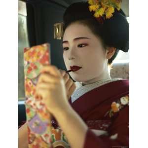  A Kimono Clad Geisha Applies Lipstick in the Back of a Cab 