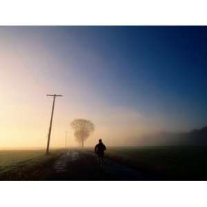  A Lone Jogger Runs Down a Rural Road in Early Morning Fog 